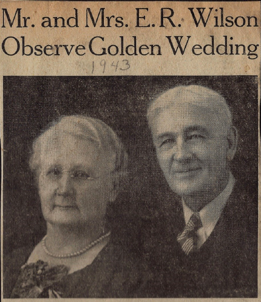 Yellowed black and white newspaper portrait photo of Edith Kowitz Wilson and Edward R. Wilson. Edith has short white hair in flat curls; she wears round wire-rimmed glasses, a dark dress with flowers at the neck, a pearl necklace, and a rather pensive expression. Ed's short white hair is parted in the middle; he wears a three-piece suit and a closed-lip smile. Above the photo is the headline: 'Mr. and Mrs. E.R. Wilson Observe Golden Wedding', below which someone has handwritten the year: '1943'.
